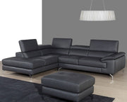Gray leather sectional sofa with ottoman in a room with a gray wall and pendant light.