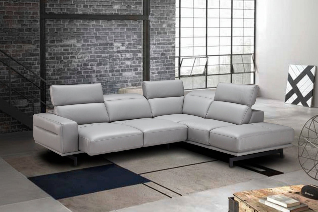 Gray sectional sofa in a modern room with brick wall and large window.