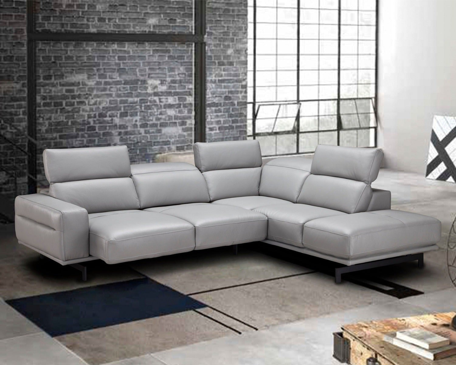 Gray sectional sofa in a modern room with brick wall and large window.