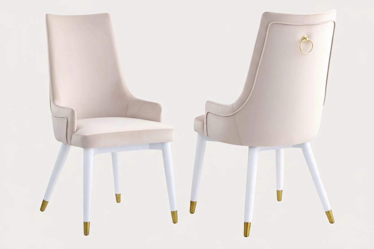 The Judy two beige chairs with white legs and gold accents on a white background