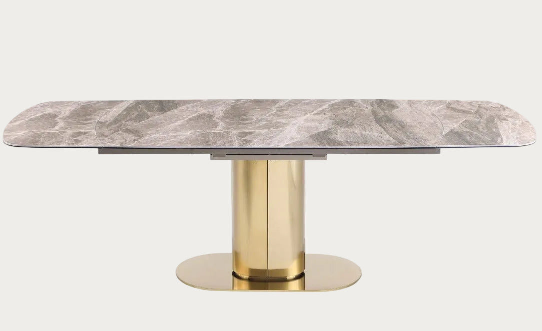 Marble-top dining table with gold cylindrical base on a white background